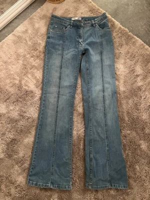 Blå bootcut jeans från Seven - Snygga blå jeans från Lindex med bootcut passform och markerade sömmar längs benen. Klassisk femficksmodell med coola bakfickor och bälteshällor. Jeansen har en lätt tvättad look och är tillverkade i jeansmaterial.