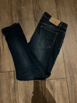 Mörkblå  jeans från Tiger of Sweden - Snygga mörkblå jeans från Tiger of Sweden  klassisk femficksdesign. Jeansen har kontrastsömmar och en beige patch med logga bak i midjan. Perfekt för dig som gillar stilrena och smala jeans.
