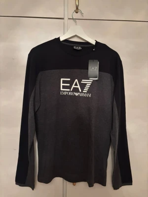 Svart och grå långärmad tröja EA7 - Snygg långärmad tröja från Emporio Armani EA7 i svart och mörkgrått. Tidigare pris på tredje bilden, helt ny. 