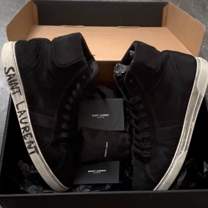Saint Laurent skor  - Svart mocka Saint Laurent skor, model: Joe high, storlek 42, mycket bra skick men märke på högra sulan, box & extra snören med följer!                        Om du har några frågor så kontakta oss gärna!!