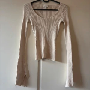 Beige ribbad långärmad topp H&M - Säljer en beige ribbad topp från H&M i storlek XS. Toppen har lång ärm, rundad halsringning och är figurnära i modellen. Materialet är mjukt och stretchigt, perfekt för en chill och snygg look. Passar dig som gillar enkla och stilrena plagg.