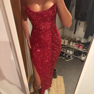 Röd glittrig långklänning Oh Polly - Säljer en röd glittrig långklänning från Oh Polly med figurnära passform, slits på sidan och axelbandslös design. Endast använd 1 gång förra året. ❤️🌹