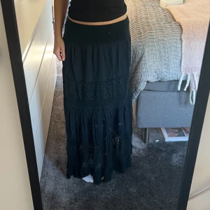 Svart långkjol med spetsdetaljer - Lång fin kjol! Köpt i somras använd fåtal gånger. Den har inget märke och igen storlek utan är istället töjbar. Jag är 1,62 och har storlek xs i vanliga fall.😊