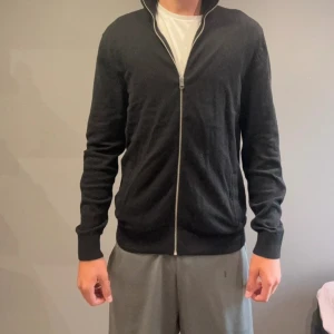 Svart helzip Jack & Jones - Svart kofta från Jack & Jones i storlek L. Tröjan har hel dragkedja framtill, ribbade muddar och en enkel, stilren design. Materialet är mjukt och stickat, perfekt för lager-på-lager under kyliga dagar. Passformen är normal och ärmarna är långa.