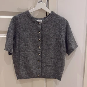 Grå stickad kofta med kort ärm - Supersnygg och gosig mörkgrå trekvarts tröja!! Aldrig använd! 🩷