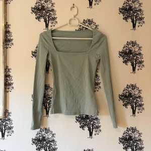 Ljusgrön långärmad topp från SHEIN - Säljer en ljusgrön långärmad topp från SHEIN i storlek XS. Toppen har en snygg fyrkantig urringning och är figurnära i modellen. Materialet är mjukt och stretchigt, tillverkat av bomull och elastan. Perfekt att styla med jeans eller kjol för en clean look.