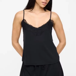Svart pyjamas sett  - Snygg svart linnetopp med tunna axelband och spets runt v-ringad halsringning. Toppen har en loose passform och är tillverkad i mjukt material som känns skönt mot huden. Perfekt för dig som gillar stilrena och feminina detaljer.