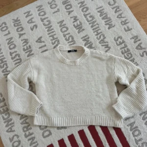 Beige stickad tröja från BikBok - Säljer en beige stickad tröja från BikBok i storlek S. Tröjan har en grovstickad struktur, rund halsringning och ribbade muddar vid ärmslut och nederkant. Perfekt för lager-på-lager under kyliga dagar.