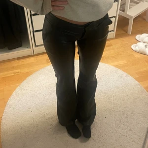 Svarta lågmidjade bootcut byxor  - Snygga svarta byxor i skinnimitation med bootcut passform och låg midja. Perfekta fest byxorna 