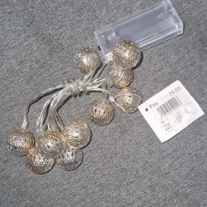 Ljusslinga - Elegant batteridriven LED ljusslinga med dekorativa metallkulor i guld. Perfekt för att skapa mysig stämning i hemmet. Transparent batteribox för 2 AA-batterier. Produkten är i nyskick med prislapp kvar.