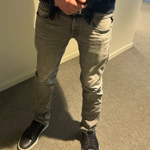 Replay Hyperflex Anbass grå jeans - Pris kan diskuteras. Säljer ett par Replay Hyperflex Anbass jeans i grå tvätt med snygga raka ben och klassiska fem fickor. Stretchigt material för extra komfort och cool Replay-logga på fickan. Passar dig som gillar stilrena och moderna jeans med smal passform.