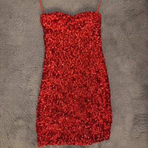 Röd glittrig paljettklänning från Man Tian - Säljer en röd glittrig kortklänning från Man Tian med tunna axelband och pass för brösten. Klänningen har en figurnära passform. Aldrig använt!☺️🌸