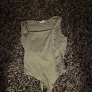 Ljusgrön ärmlös bodysuit från Aritcot - Säljer en stilren ljusgrön bodysuit från Aritcot. Den är ärmlös med rundad halsringning och knäppning i grenen. Tillverkad i mjuk bomull, perfekt att styla med jeans eller kjol för en clean look.