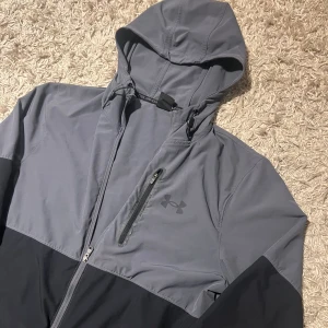 Under armour vindjacka grå svart herr M  - Säljer en under armour vindjacka i strlk M. Mycket bra skick inga defekter. Postas antigen samma dag som köp eller dagen därpå🙌💯
