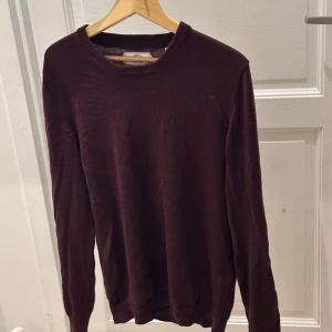 Vinröd stickad tröja These Glory Days - Snygg vinröd stickad tröja från These Glory Days med rund hals och lång ärm. Tröjan har en enkel och clean design som funkar till många olika stilar. Materialet är mjukt och skönt, perfekt för kyliga dagar. Skandinavisk design med klassisk passform.
