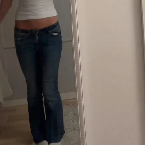 Blå bootcut jeans - Säljer ett par klassiska blå VEROMODA jeans med bootcut passform och låg midja. Jeansen har fem fickor, knapp och dragkedja framtill samt snygga slitningar. Perfekt för dig som gillar en avslappnad och tidlös stil.