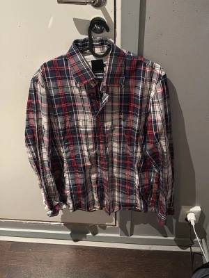 Rutig skjorta Riccovero X-Slim Fit - Säljer en snygg rutig skjorta från Riccovero i X-Slim Fit. Skjortan har lång ärm, klassisk krage och knappar framtill. Färgerna är marinblå, röd och vit vilket ger en fräsch och ungdomlig look. Perfekt för dig som gillar smal passform och stilren design. Det är storlek L men eftersom det är extraslim fit så sitter den mer som M