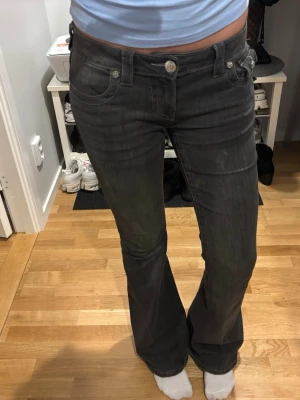 True Religion Joey Low Rise Flare Jeans - Säljer ett par svarta True Religion Joey jeans med låg midja och flare-ben. Jeansen har klassiska fem fickor, silverfärgade knappar och kontrastsömmar. Materialet är jeans och passformen är loose med riktigt snygg bootcut-stil. Använda men super bra skick! ❤️