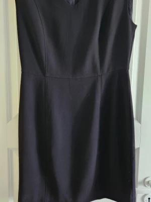 Svart ärmlös klänning Part Two - Klassisk svart ärmlös klänning från Part Two i storlek 40. Klänningen har en enkel, stilren design med v-ringning och markerad midja. Perfekt för dig som gillar minimalistisk stil och vill ha något tidlöst i garderoben.