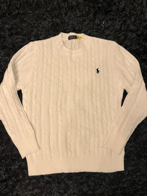 Vit kabelstickad tröja Polo Ralph Lauren - Kabelstickad vit tröja från Polo Ralph Lauren .Perfekt för dig som gillar stilrena och schyssta plagg.