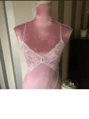 Vit spetlinne med smala band - Söt vit linne med tunna axelband och spetsdetaljer framtill. Västen har en v-ringad form och är gjord i ett tunt, genomskinligt material som ger en feminin och romantisk känsla. Perfekt att styla över ett linne eller t-shirt för en trendig look.