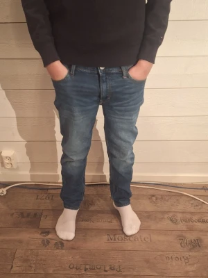 Blå jeans straight fit - Säljer ett par klassiska blå jeans med straight fit. Jeansen har normal midja, fem fickor och snygga slitningar framtill för en avslappnad look. Tillverkade i tåligt denimtyg som passar perfekt till vardagsstilen.
