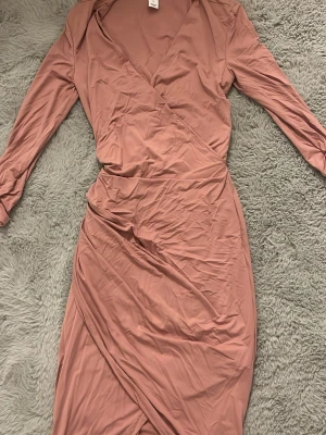 Rosa omlottklänning från NLY One - Säljer en snygg rosa omlottklänning från NLY One i storlek S. Klänningen har lång ärm, v-ringning och en smickrande omlottmodell som ger en feminin siluett. Tillverkad i ett mjukt och följsamt material.