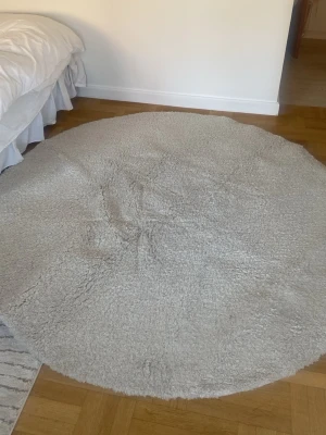 Matta rund  - Bilderna visar en rund, fluffig matta i ljusbeige färg