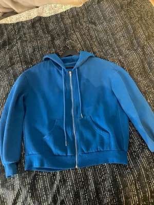 En blå zip hoddie - Det är en blå zip hoodie som är ett skönt tyg perfekt för både sommar och vinter