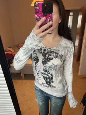 Vit långärmad topp Molly-Jo M - Säljer en vit långärmad topp från Molly-Jo i storlek M. Tröjan har tryck med western/cowboy-tema, glittriga detaljer och text både fram och bak. Materialet är mjukt och stretchigt, och passformen är normal. Perfekt för dig som gillar unika prints och coola detaljer.