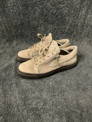 Beige Zanotti vinterskor - Säljer ett par beige zanotti sneakers i mocka med snörning och dragkedjor på sidorna. Skorna har en svart platt sula, Insidan är mjuk och fodrad.