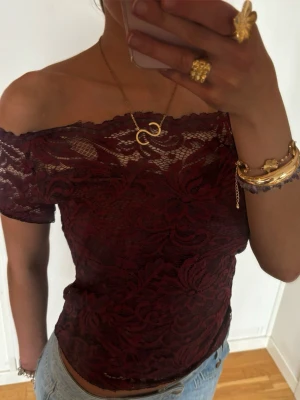 Vinröd offshoulder spetsblus - Säljer en vinröd offshoulder blus i genombruten spets med korta ärmar. Toppen har ett blommigt spetsmönster och sitter tight mot kroppen. Jag är 168 och det är mina bilder, köp via köp nu direkt eller Swish, kvar tills markerad som såld 💖 