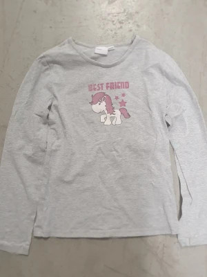 Tröja - Söt grå långärmad tröja från mywear young i storlek 134/140. Tryck framtill med en gullig unicorn, rosa stjärnor och texten 'Best Friend'. Perfekt för dig som gillar mjuka och bekväma plagg med roliga motiv.