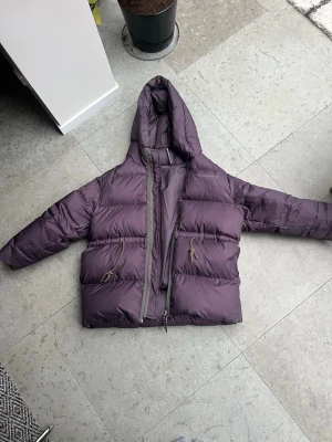 Lila pufferjacka från Acne Studios - Säljer en oversized lila pufferjacka från Acne Studios med huva och dragkedja. Skickar direkt! 