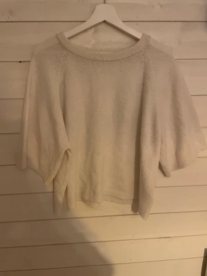 Ljus stickad tröja med kort ärm - Enkel och stilren ljus stickad tröja med korta, vida ärmar och rund hals. Perfekt för lager på lager och funkar året runt. Mjuk och skön känsla, lätt att matcha med olika outfits.  Lappen är bortklippt, storlek M-L från lager157