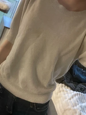 Beige stickad topp från Nelly - Säljer en beige stickad topp köpt på Nelly med rund halsringning och ribbade kanter. Toppen har korta ärmar med lätt puff och är gjord i mjukt material som känns skönt mot huden. Perfekt till jeans eller kjol. Aldrig använd. Pris kan diskuteras