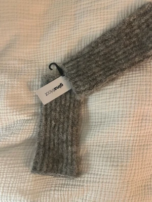 Grå stickade handledsvärmare Gina Tricot - Säljer ett par mjuka och fluffiga handledsvärmare från Gina Tricot helt oanvända med prislapp på i grå melerad ton. De är ribbstickade och har en enkel, rak form som passar perfekt till kalla dagar. Materialet är en mysig ullmix som håller dig varm och stilen är klassisk och enkel. Skriv om ni vill ha fler bilder 💗
