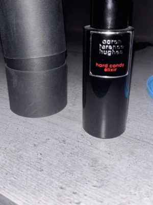 Aaron Terence Hughes Hard Candy Elixir - Byten går bra, ca 35 ml i flaskan.Unik parfymflaska i svart från Aaron Terence Hughes med namnet Hard Candy Elixir. Flaskan har en modern, cylindrisk form och en svart etikett med röd text. Perfekt för dig som gillar exklusiva och trendiga dofter.