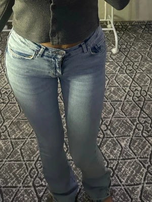 Ljusblå raka jeans med låg midja - Säljer ett par ljusblå jeans med låg midja och raka ben. Jeansen har klassisk femficksdesign och stängs med dragkedja och knapp. Perfekta för en avslappnad och trendig look. Materialet är denim i bomull.
