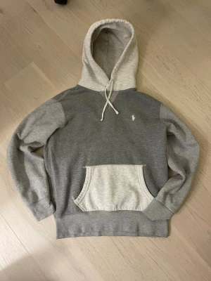Grå hoodie från Polo Ralph Lauren - Snygg grå hoodie från Polo Ralph Lauren med ljusgrå huva och magficka. Klassisk broderad logga på bröstet. Perfekt för en avslappnad och stilren look. Kom privat om du har frågor! 