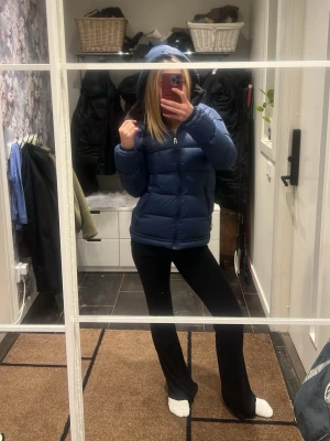 Mörkblå pufferjacka med huva - Säljer en mörkblå pufferjacka med dragkedja och huva. Jackan har en klassisk quiltad design och är perfekt för kalla dagar. Den är lätt vadderad och har en stilren look som passar till det mesta.