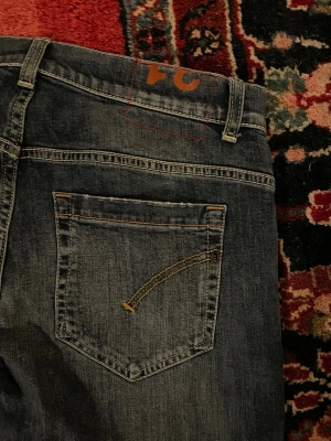 Dondup Jeans W31 – Nästan Ny, Fabriksslitningar  - Säljer ett par Dondup jeans i storlek W31, men de passar även större storlekar. Jeansens slitningar är fabriksgjorda och de är i nästan nyskick.  Mått: 	•	A: 40 cm 	•	B: 80 cm 	•	C: 20 cm 	•	D: 15 cm  Perfekta för dig som vill ha ett par lyxiga, moderna jeans med stilrena detaljer. ⚜️