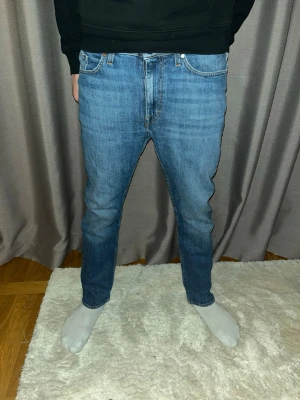 Blå Jeans Tiger of Sweden straight fit - Klassiska blå tiger of Sweden jeans med rak passform och fem fickor. Jeansen har knappgylf och är tillverkade i slitstark bomullsdenim. Passar en person mellan 155 -170 cm 