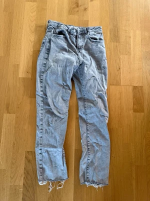 Gråa raka jeans från Zara - Snygga grå jeans från Zara med rak passform och slitna benslut. Jeansen har en ljusgrå tvätt och är tillverkade i bomull med lite stretch för extra komfort.