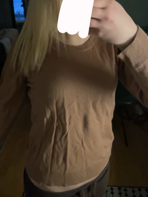 Beige basic tröja med rund hals - En enkel och stilren beige tröja med rund halsringning och långa ärmar. Tröjan har ribbade muddar vid ärmslut och nederkant, perfekt för lager-på-lager. Passar till både jeans och mjukisbyxor för en avslappnad look.