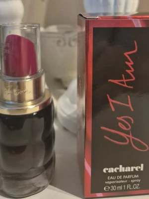 Cacharel Yes I Am Eau de Parfum 30ml - Cacharel Yes I Am Eau de Parfum i 30 ml flaska. Flaskan har en unik design som liknar ett läppstift med svart och guld detaljer samt en röd topp. Doften är feminin och modern, perfekt för dig som vill sticka ut med en snygg parfymflaska i samlingen. ANVÄND 3 GGR
