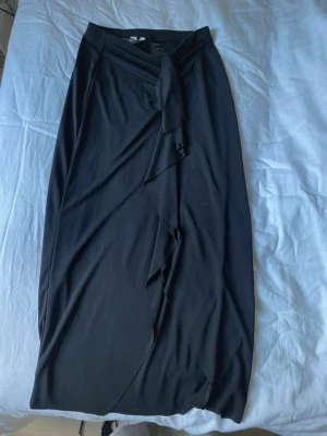 🖤 Svart omlottkjol från H&M – storlek XS - Svart omlottkjol från H&M i storlek XS. Använd fåtal gånger och i mycket fint skick. Säljer eftersom den tyvärr inte kommer till användning längre. Smickrande omlottdesign med knytning i midjan