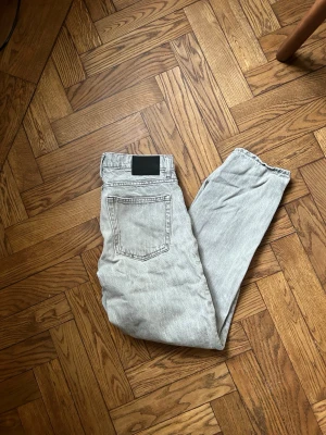 Ljusgrå raka jeans - Säljer ett par ljusgrå jeans med rak passform och klassisk femficksdesign. Jeansen har en svart patch bak i midjan och är tillverkade i ett slitstarkt denimtyg. Det finns ett litet litet hål i byxorna som man kan se på bilden. Jeansen är från vailent. Funkar perfekt 👌🏻 