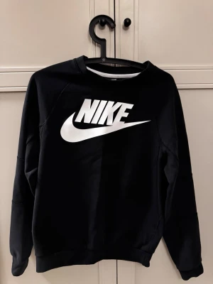Svart Nike sweatshirt XS - Säljer en svart sweatshirt från Nike i storlek XS. Tröjan har en stor vit Nike-logga framtill och klassisk rund halsringning. Perfekt för dig som gillar sportig och enkel stil. Tillverkad i mjukt material för extra komfort.