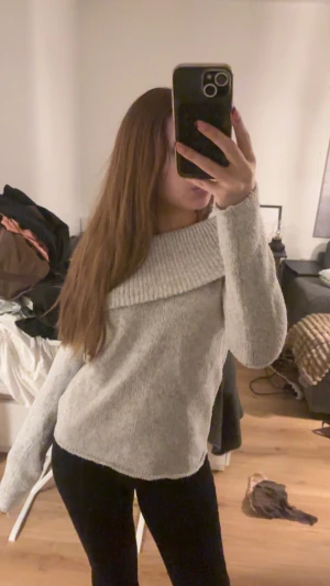 Ljusgrå stickad offshoulder tröja - Supermysig ljusgrå stickad tröja med bred offshoulder-krage som ger en chill och snygg vibe. Mjuk och skön, perfekt för kalla dagar. Långärmad och loose passform, passar dig som gillar avslappnad stil.